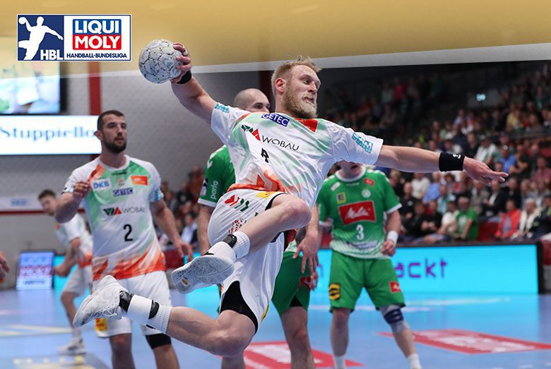 Matthias Musche im weißen SCM-Trikot setzt am Ball im Sprungwurf zum Torwurf an.