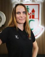 Porträt von Vermögensberaterin Sandra Bittl im schwarzen SCM-Polo-Shirt vor dem Vereinslogo