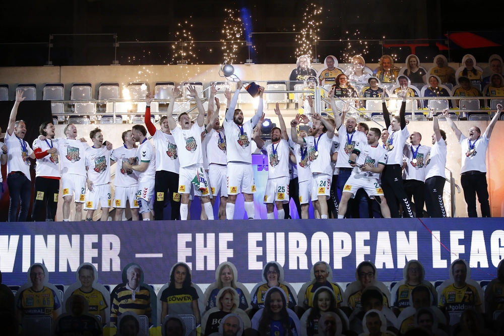 Die Mannschaft des SC Magdeburg stemmt jubelnd den Pokal der EHF European League auf dem Siegerpodest in die Höhe