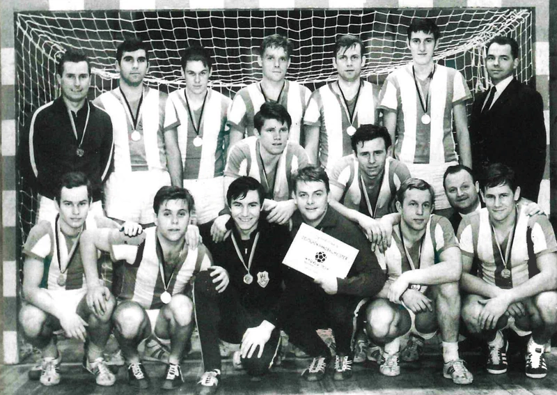 Schwarz-Weiß-Mannschaftsfoto des SC Magdeburg als DDR-Hallenhandballmeister 1970 mit Medaillen vor dem Tor.