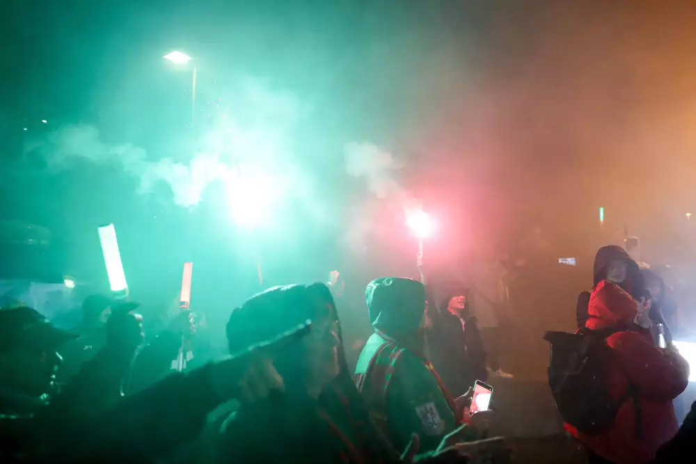 SCM-Fans feiern den Club-Weltmeistertitel nachts mit grün-roten Leuchten.