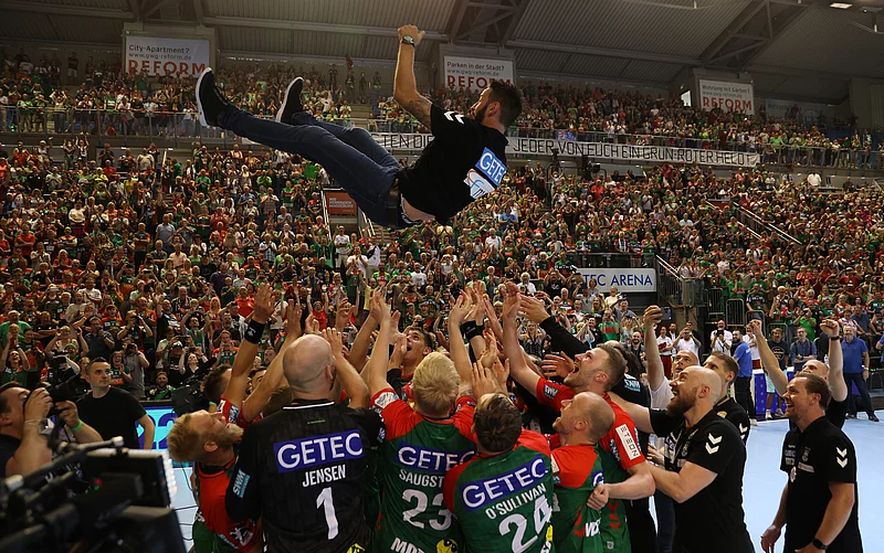 SCM-Trainer Bennet Wiegert wird nach dem Gewinn der deutschen Meisterschaft von seiner Mannschaft in einer vollen Arena in die Luft geworfen.